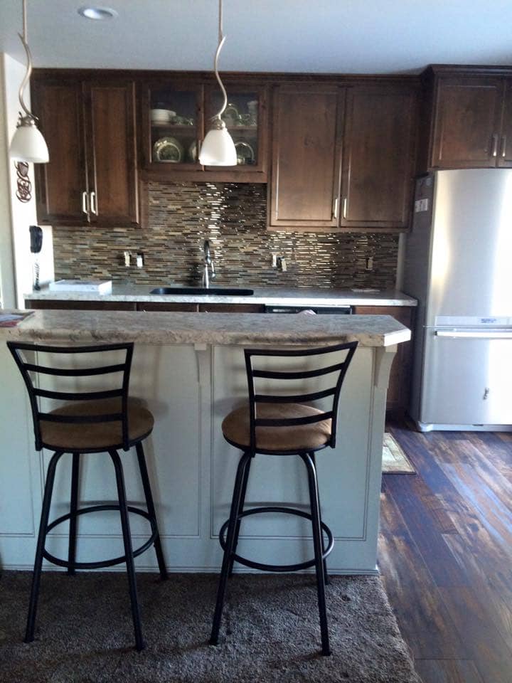 Rustic Alder Kitchen Cabinets with Tile Backsplash and a New Kitchen Island with a Raised Snack Bar and Cook Top